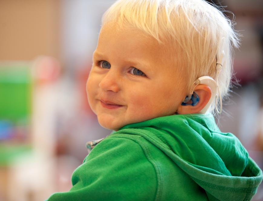 Das Bild zeigt ein lächelndes Kind mit Cochlea Implantat.