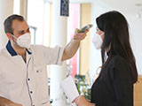 Das Bild zeigt eine Besucherin beim Fiebermessen