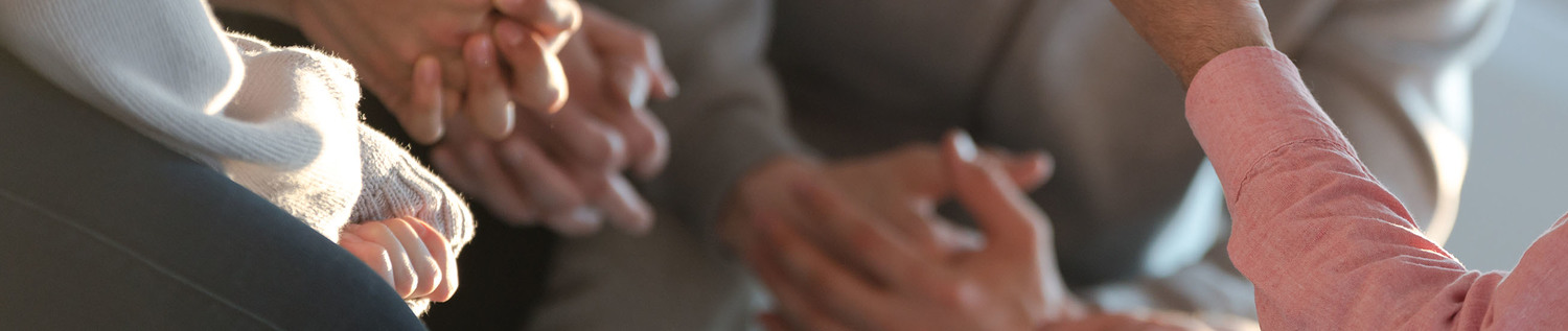 Close-up of a therapist gesticulating while talking to a group of listing teenagers during an educational self-acceptance and motivation meeting.