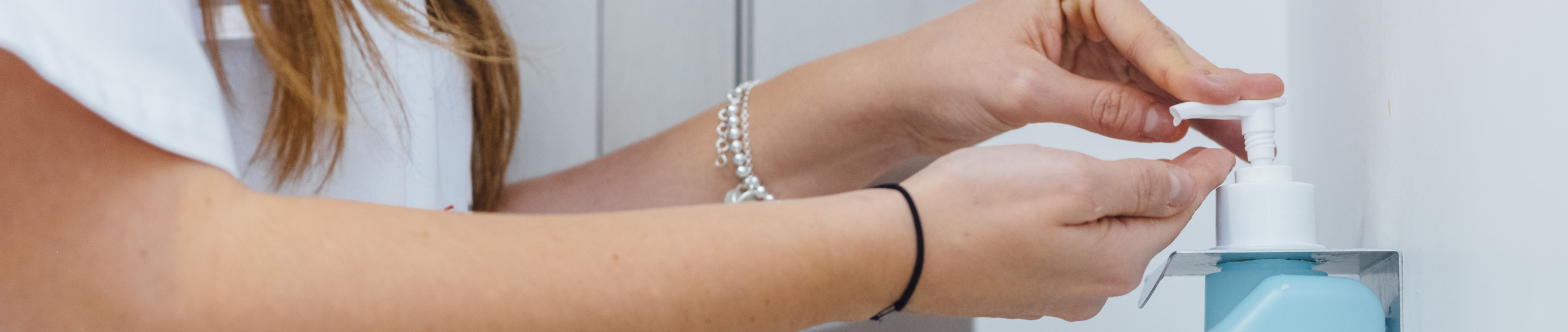 Medic in white coat disinfecting hands in clinic