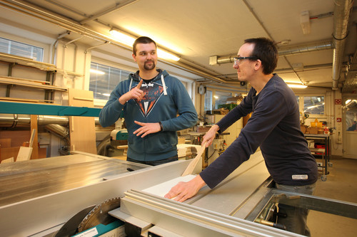 Betreuer mit dem Assistenten beim Holz zuschneiden