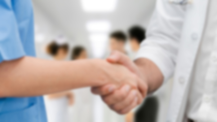 Doctor in hospital handshake with another doctor. Healthcare people teamwork and medical service concept.