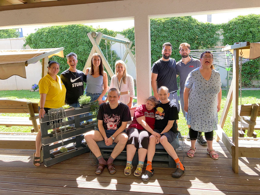 Das Team der TWS Pedro Velasco mit Mitarbeitenden der Firma Knapp auf den von der Firma gespendeten Paletten-Möbeln.