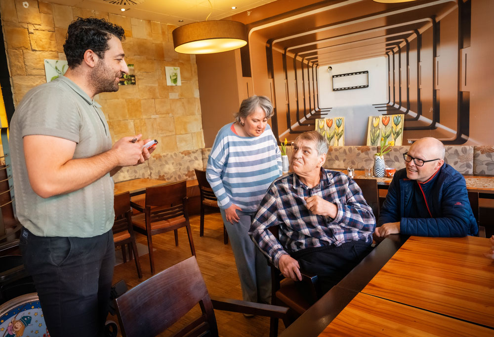 Ein Teil des Teams der TWS Antonio Martin beim Bestellen mit dem Kellner in der Pizzeria.