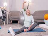 Das Bild zeigt eine ältere Dame bei Gymnastikübungen auf einer Matte.
