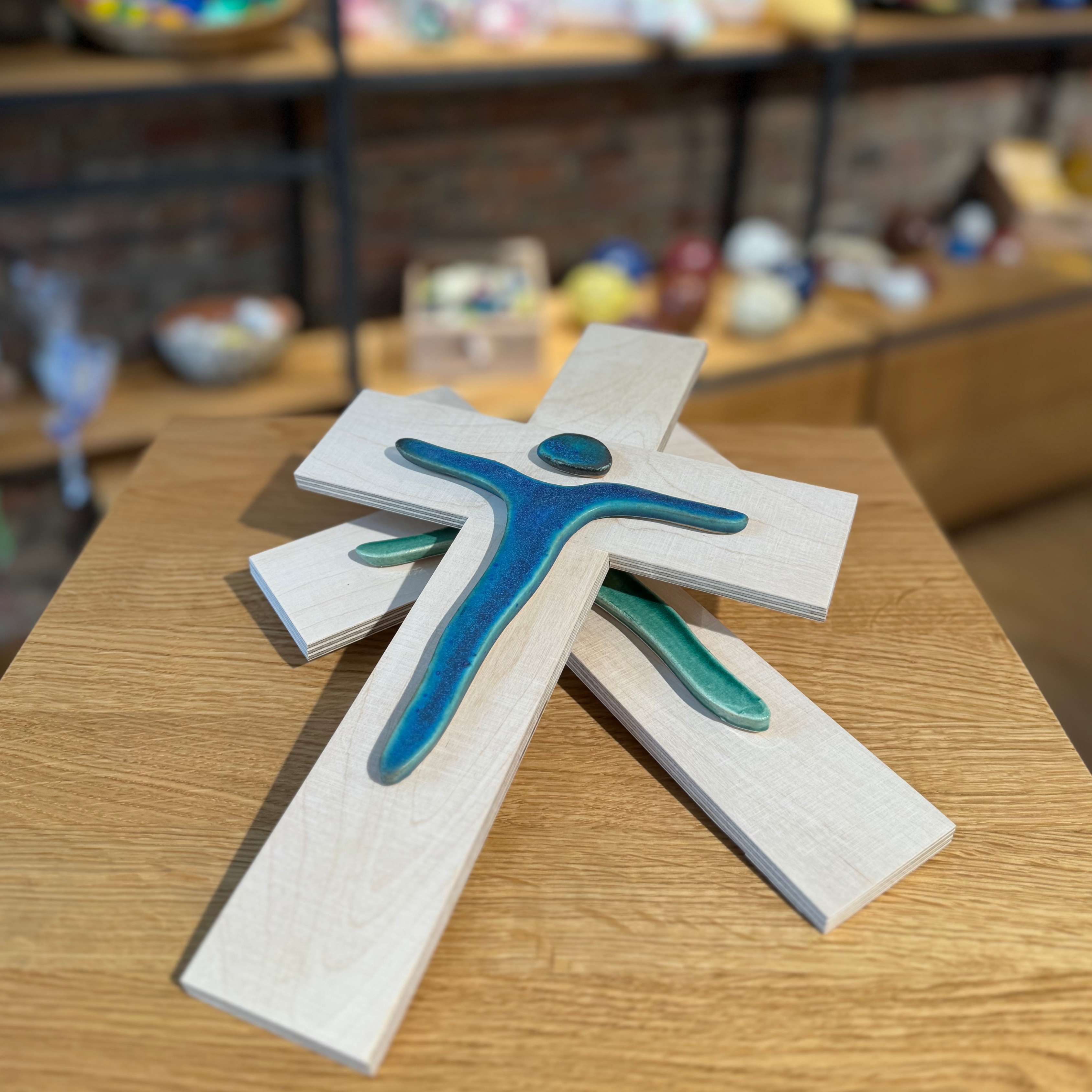 Holzkreuze mit minimalistisch designten Jesus in blau und grün.   