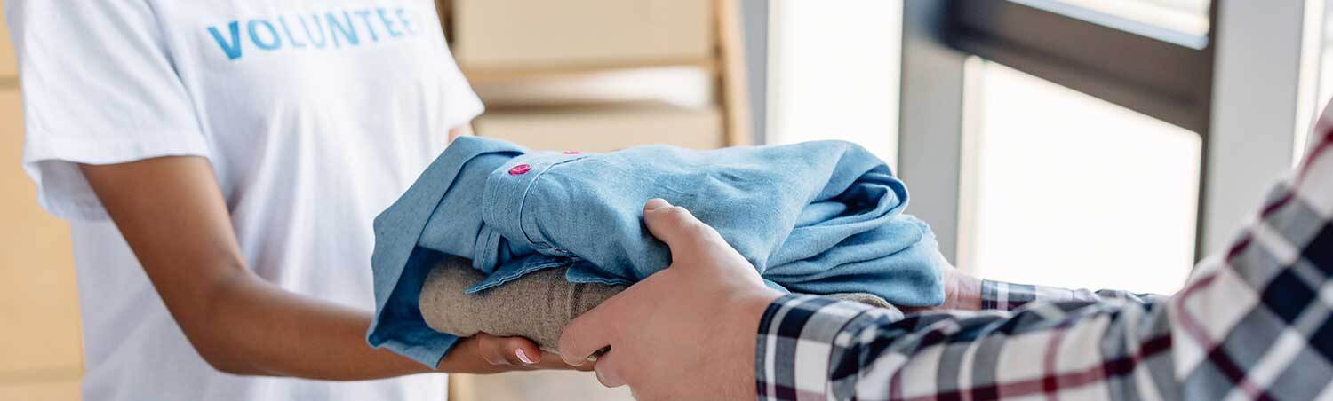 Das Bild zeigt die Übergabe von Wäsche an eine bedürftige Person.