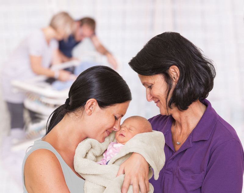 Das Bild zeigt eine Mutter mit ihrem Baby und einer Hebamme