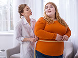 Das Bild zeigt eine übergewichtige Frau, deren Bauchumfang von einer Ärztin gemessen wird.