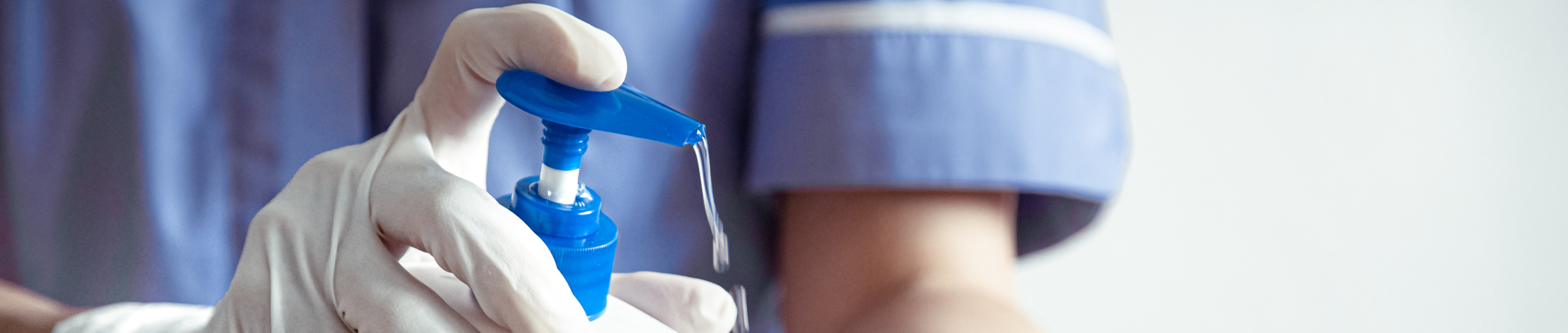 Doctor in a blue coat and protective gloves. The use of a disinfectant with gloves. Personal hygiene and virus protection concept.