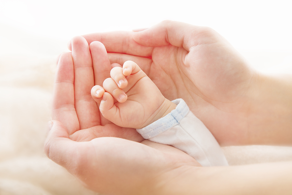 Newborn baby hand in mother hands. Help and assistance concept, close up.