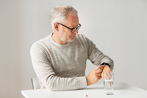 Das Bild zeigt einen Mann bei der Einnahme seiner Medikamente.