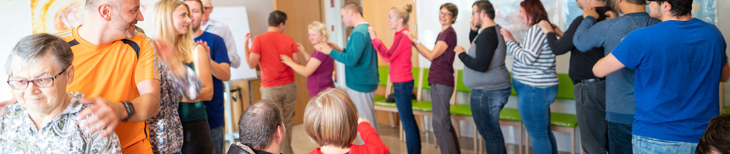 BewohnerInnen und BetreuerInnen stehen aufgereiht hintereinander bei einem Bewegungsspiel