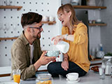 Das Bild zeigt das Cover des Granatapfel Magazins 4/2023 mit einer Frau und einem Mann, die ihr Frühstück zubereiten.