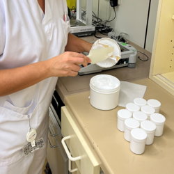 Man sieht eine Kollegin in der Aufbereitung einer Salbe. 