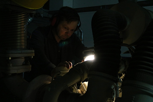 Das Bild zeigt einen Techniker mit Generator im Dunkeln