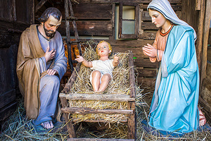 Das Bild zeigt Krippenfiguren vom Jesuskind, Maria und Josef im Stall.