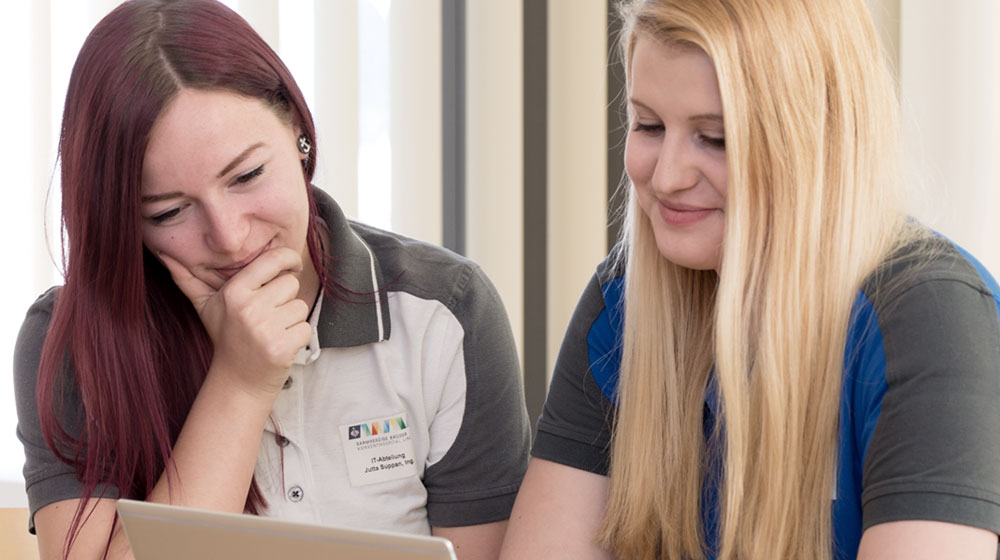 Das bild zeigt zwei IT-Mitarbeiterinnen ein gemeinsames Thema bearbeitend.