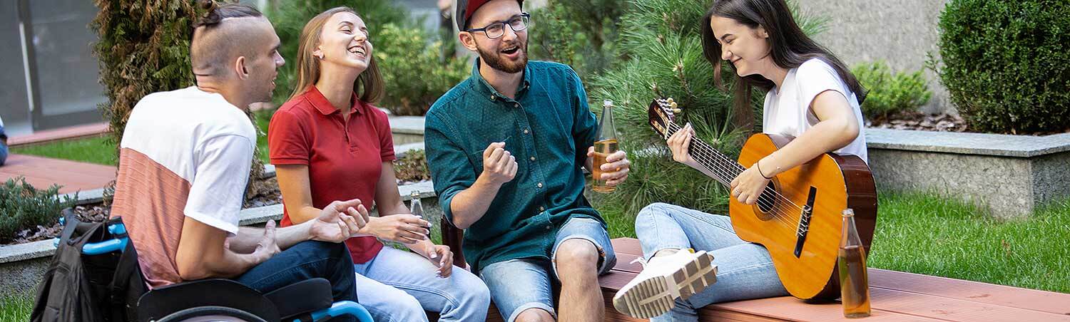 Das Bild zeigt eine Gruppe junger Menschen, ein Mann sitzt in einem Rollstuhl.