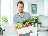 Das Bild zeigt einen Mann mit einem Korb voller Gemüse.