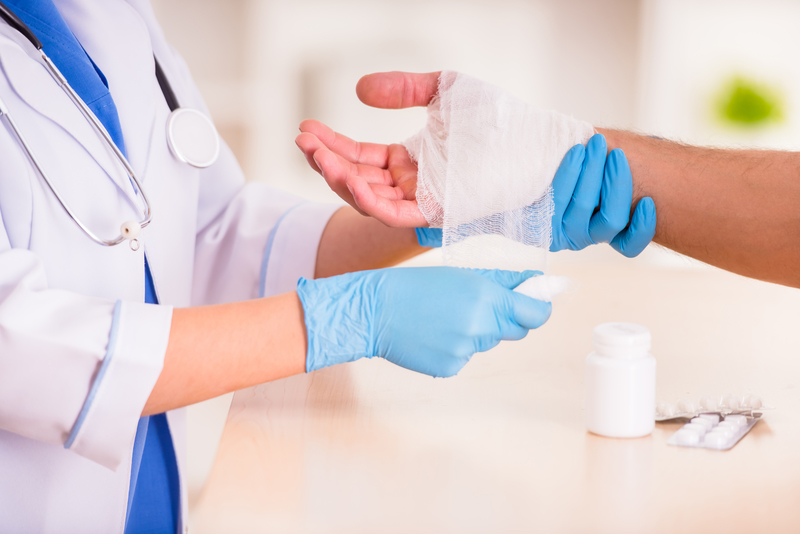 Injury man in doctor Injury hands. Young man with injured hands. Young woman doctor helps the patient