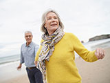 Das Bild zeigt eine Frau und einen Mann bei eine ausgelassenen Strandspaziergang.