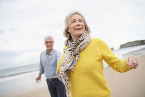 Das Bild zeigt eine Frau und einen Mann beim Spaziergang am Strand.