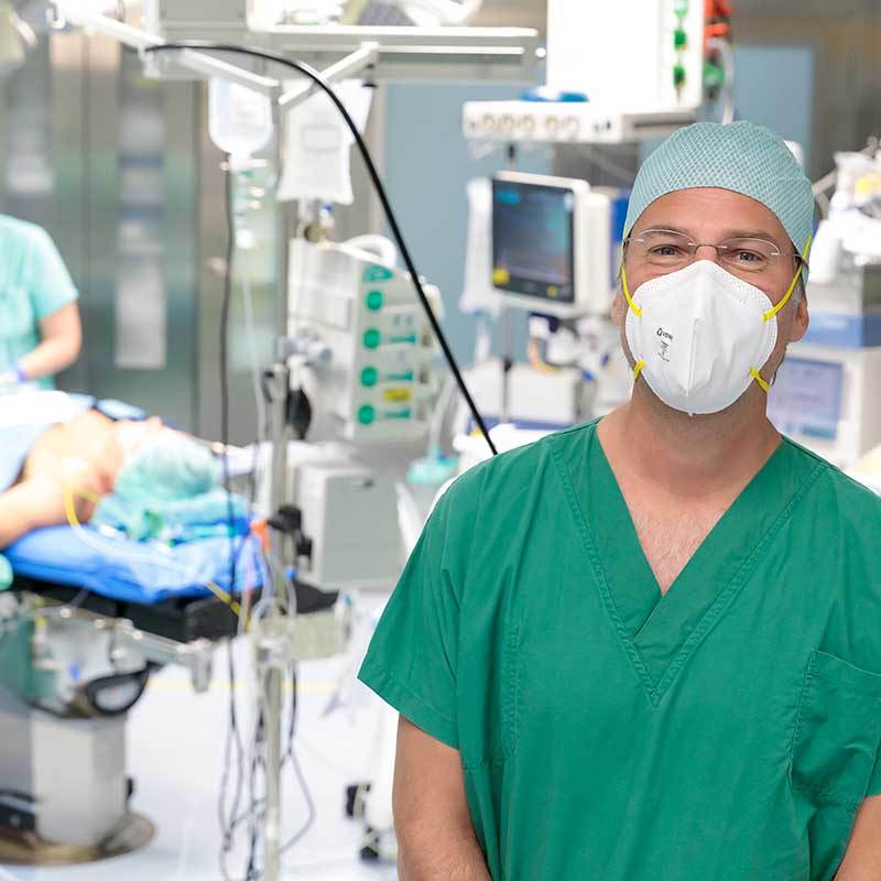 Medizinisches Fachpersonal mit OP-Kleidung und FFP2-Maske im Operationssaal.