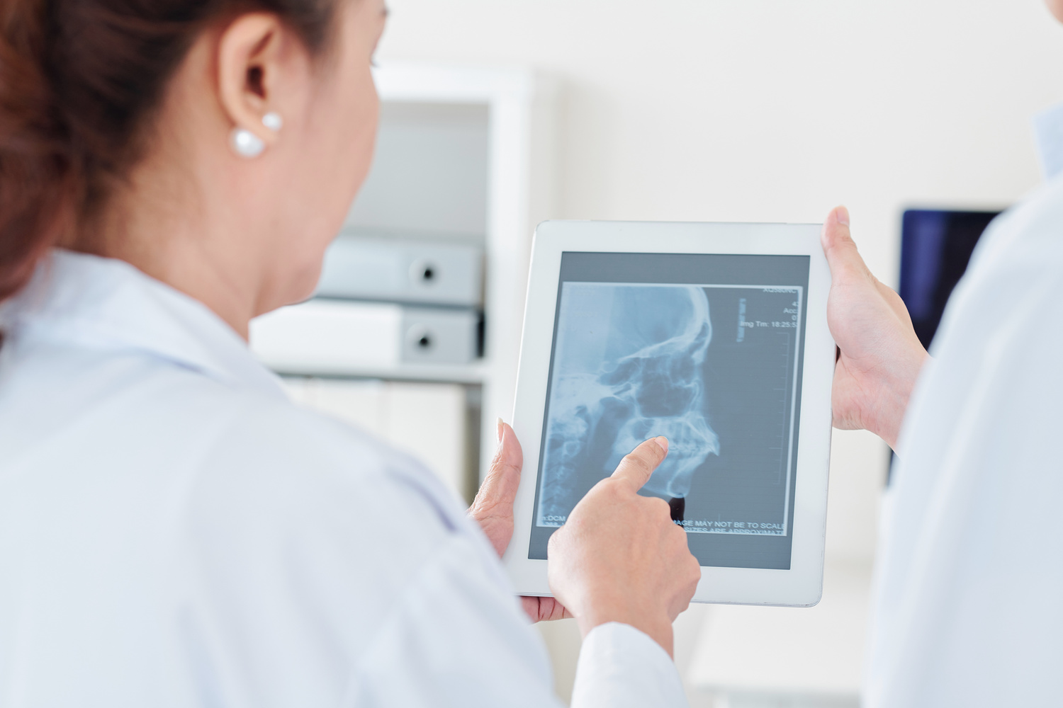 Neurologist and radiologist discussing scull x-ray of patient on tablet computer in medical office