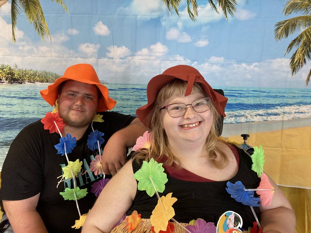 Die Fotobox war der Hit. Das Bild zeigt einen jungen Mann und eine junge Frau mit Blumengirlande für einem tropischen Palmenstrand