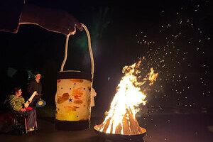 Eine selbstgebastelte Laterne, im Hintergrund sieht man ein Lagerfeuer.