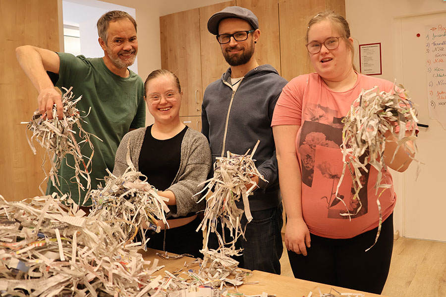 Papierschnipsel für Tiere in Not-Granatapfel-Magazin-02-2024-Barmherzige-Brueder-900x600 / Barmherzige Brüder Kainbach/Daniel Kriwitz Das Bild zeigt drei Klient:innen der der Tageswerkstätte Andreas mit dem produzierten Einstreu aus Papierschnipseln.