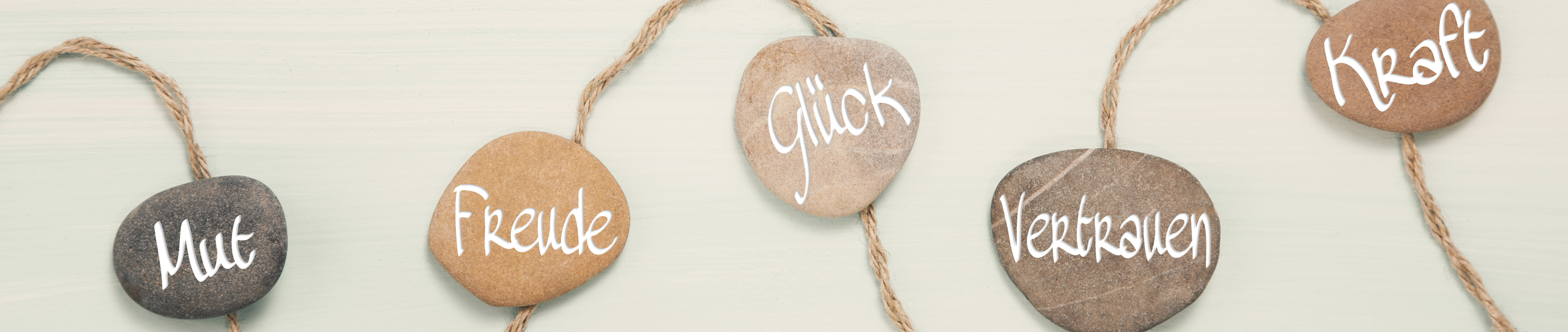 Five stones with german text for: courage, happiness, luck, trust and power. 