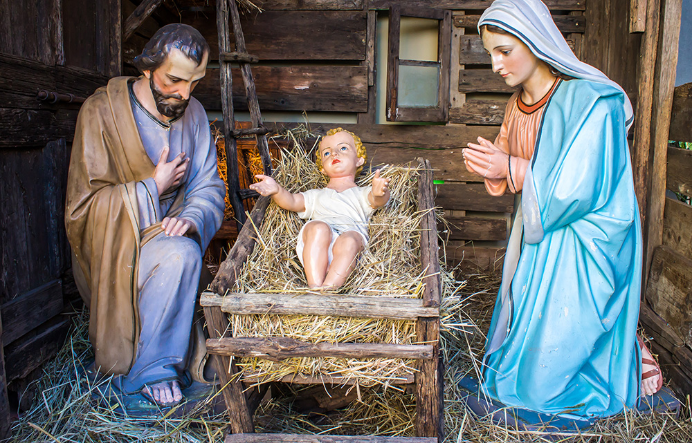 Das Bild zeigt Krippenfiguren vom Jesuskind, Maria und Josef im Stall.