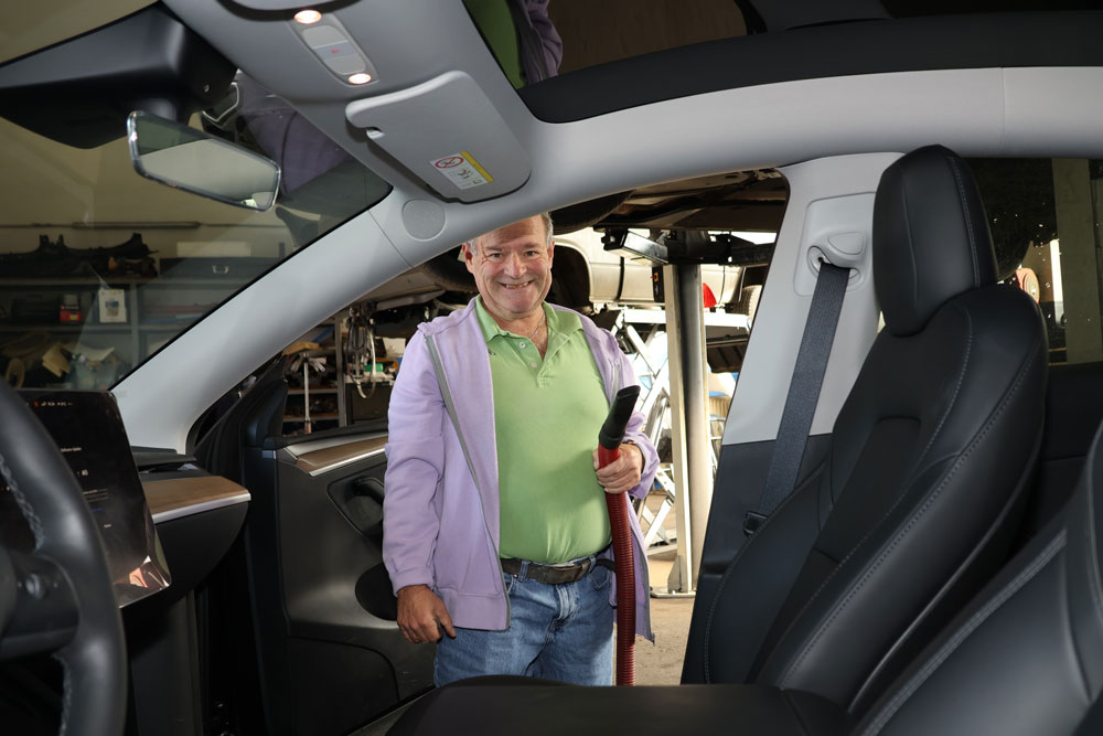 Bernhard mit dem Autostaubsauger in der Hand, während er in der geöffneten Beifahrertür steht.