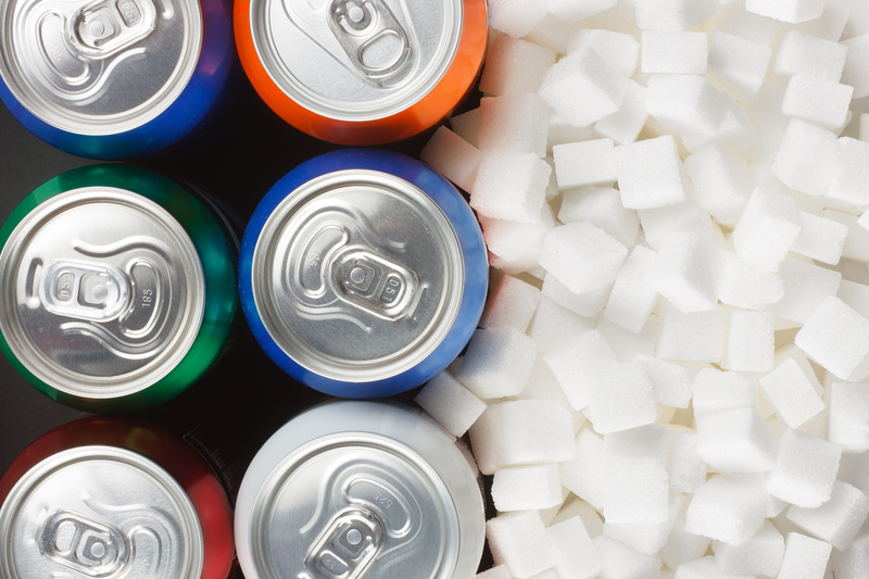 Unhealthy food concept - sugar in carbonated drinks. Sugar cubes as background and canned drink