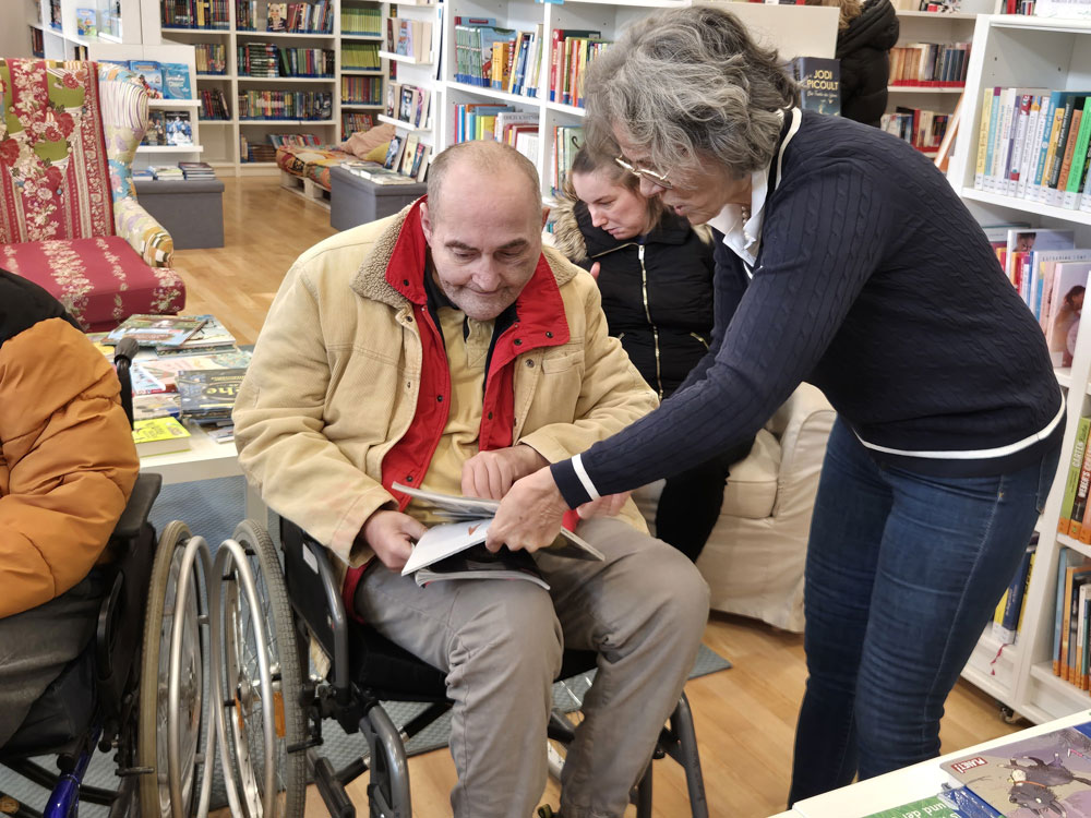 Heider sucht sich in der Bibliothek ein Buch aus und wird von einer Mitarbeiterin beraten.