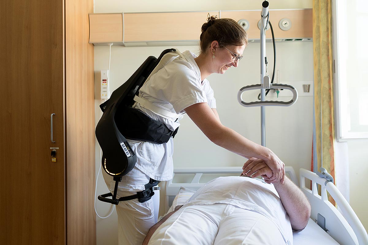 Das Bild zeigt eine Mitarbeiterin mit einem Exoskelett.