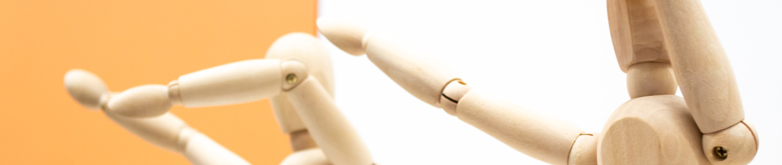 Two wooden human figures on white and orange backgrounds dance and make a dab movement sneezing gesture.