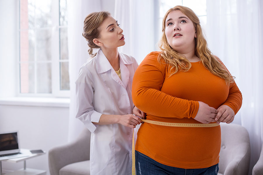 Das Bild zeigt eine übergewichtige Frau, deren Bauchumfang von einer Ärztin gemessen wird.