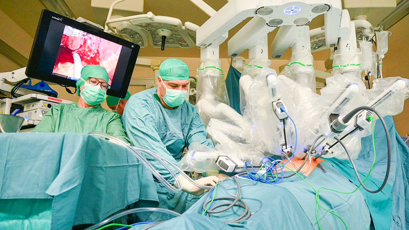 Arzt und sterile Pflegekraft mit Operationsroboter